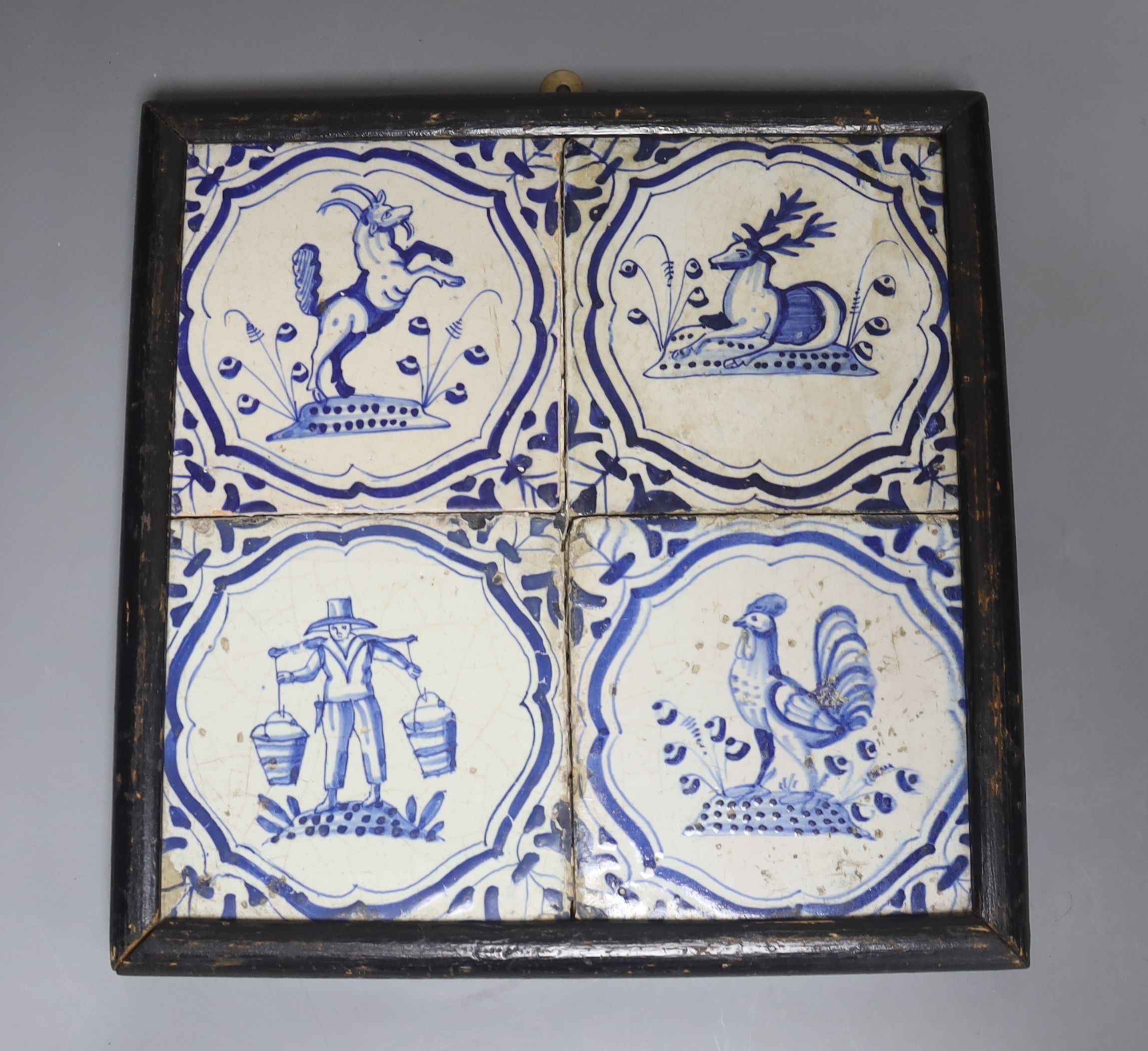 Four 18th century Dutch Delft blue and white tiles, decorated with deer, cockerels and figures within shaped panels (frame 29cm)